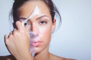 Lady peeling off face mask with large pores