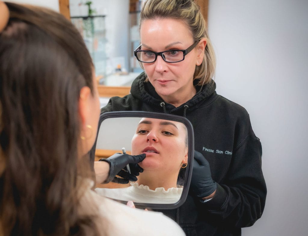 Showing the patient the results of her lip filler aesthetic treatment.