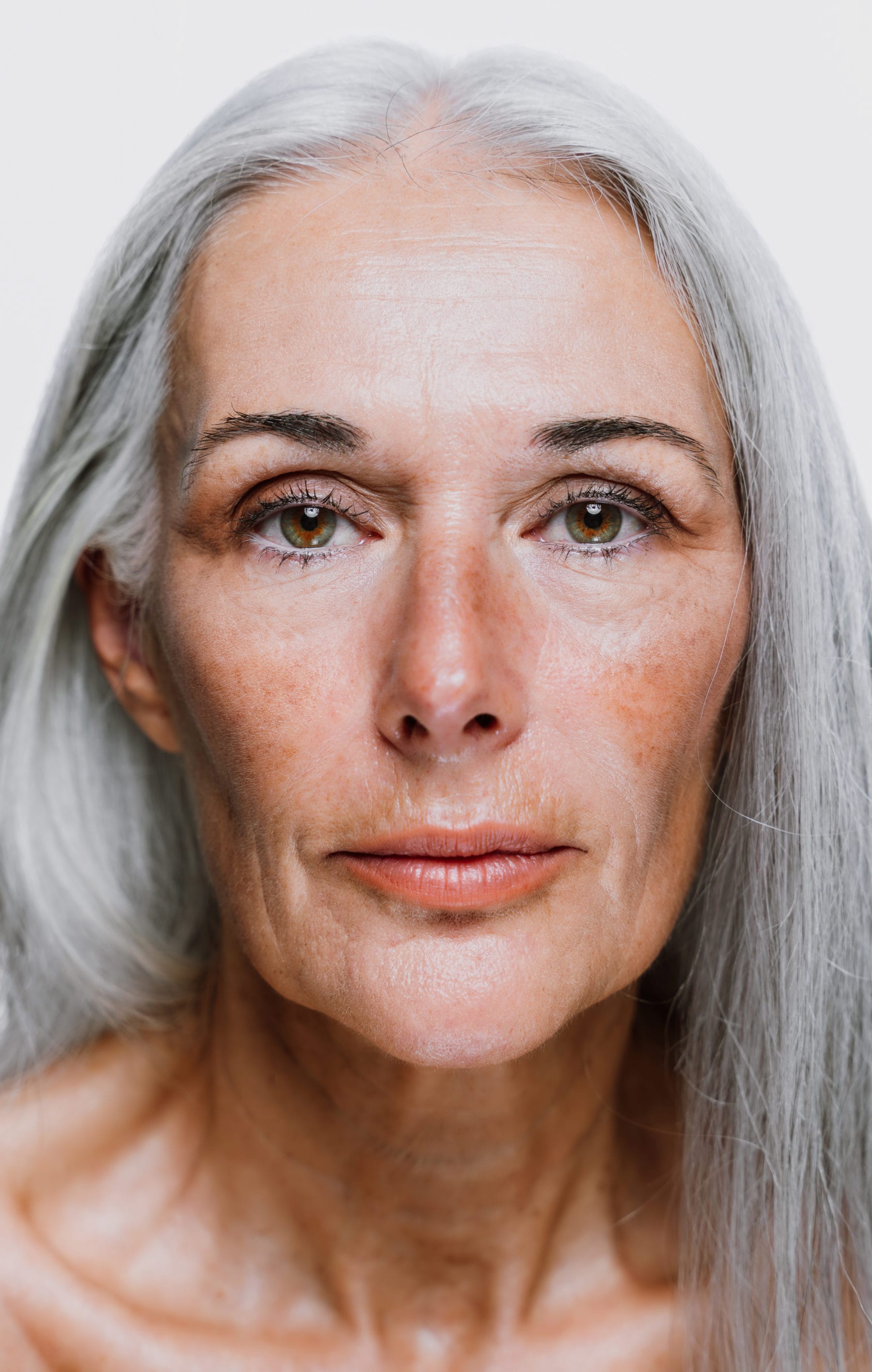 Senior woman with flowing grey hair and hyperpigmentation
