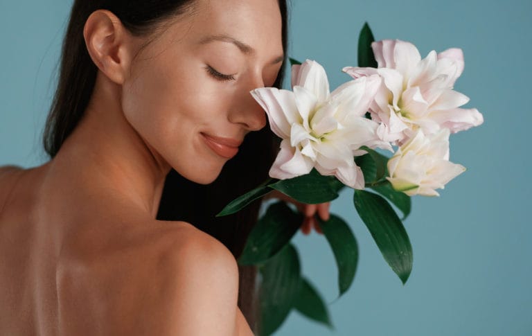 Portrait, woman holding lily flower. Young woman is i to display skin sensitivity